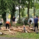 Vrijwilligers schillen hout voor de klauterbrug Vrijwilligers schillen boomstammen voor de klauterbrug